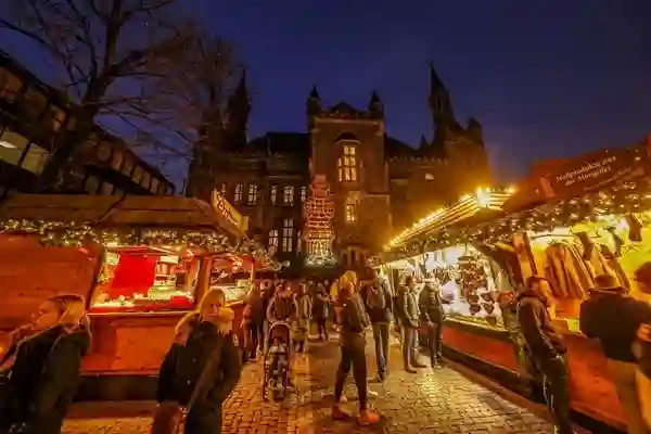 Marché de Noël d’Aix-la-Chapelle en soirée. L’image met en valeur les charmantes stalles en bois illuminées avec en toile de fond la cathédrale d’Aix-la-Chapelle, créant ainsi une atmosphère magique.