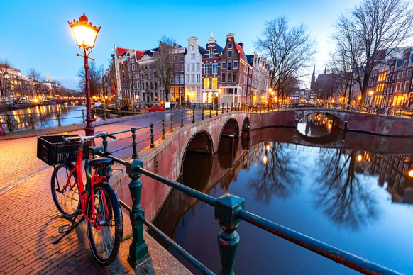 Voyage d'une journée à Amterdam en autocar Amsterdam, offrant une expérience confortable pour explorer la ville, ses ponts emblématiques et ses bateaux naviguant sur le fleuve.